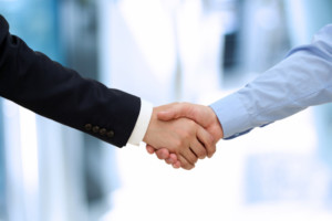 Image of a firm handshake between two colleagues in office.